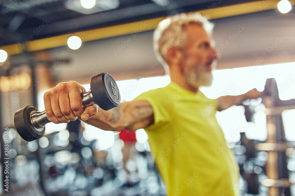 Senior adult performing a lateral raise with light dumbbells 