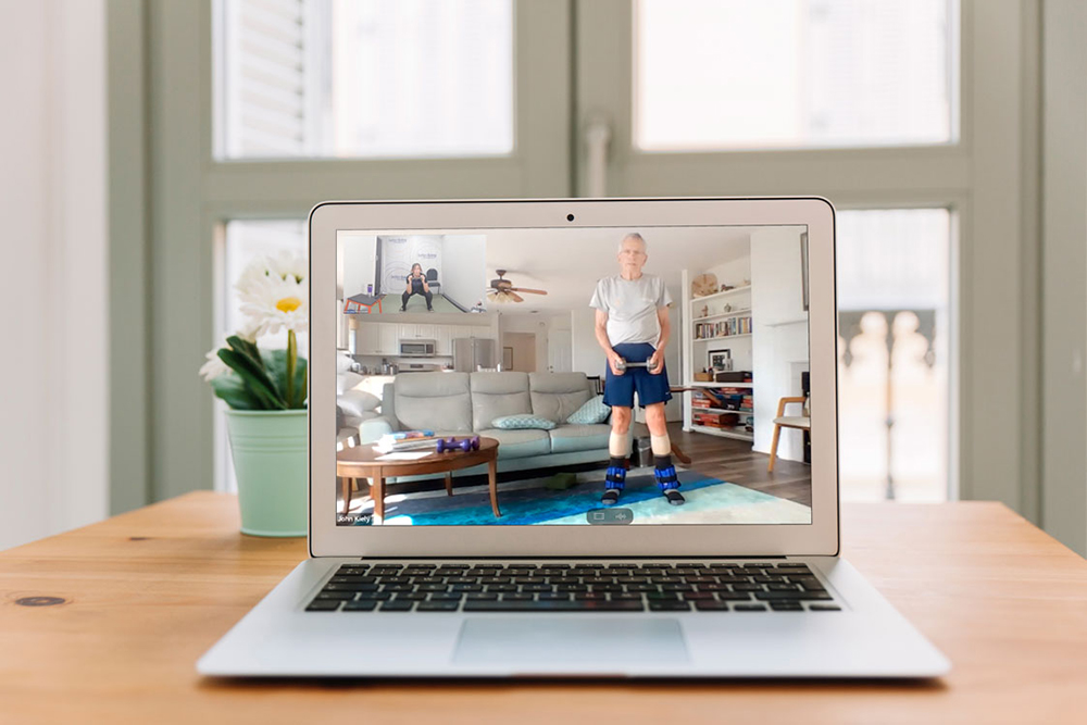 Shot of computer with senior adult exercising with free weights at home 